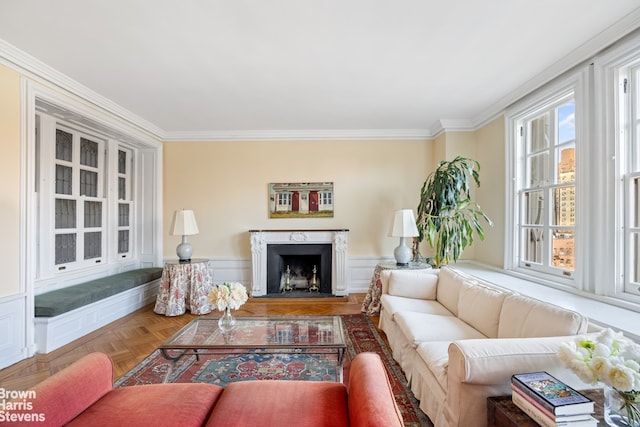 living area featuring a fireplace, a wainscoted wall, and ornamental molding