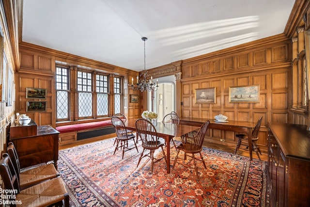 dining area featuring an inviting chandelier, a decorative wall, visible vents, and ornamental molding