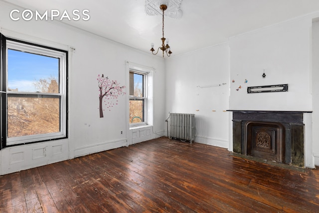 1044 Lafayette Ave, New York City, NY 11221 - unfurnished living room with radiator, a chandelier, hardwood / wood-style flooring, ornamental molding, and a fireplace