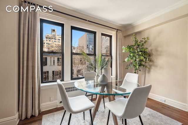 dining area featuring crown molding, baseboards, and wood finished floors