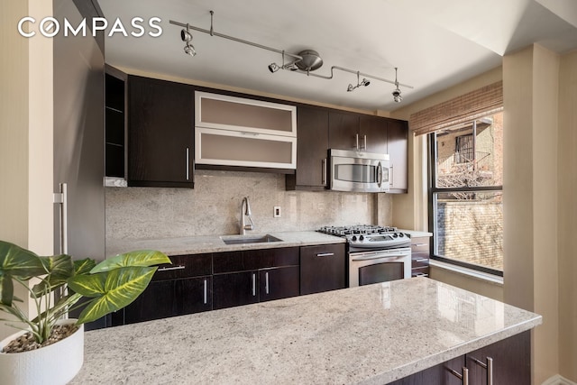 kitchen with stainless steel appliances, a sink, dark brown cabinets, and backsplash