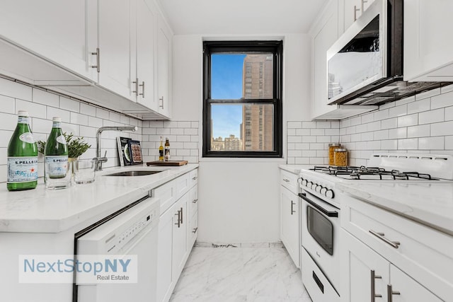 kitchen with a sink, light stone counters, white cabinets, and white appliances