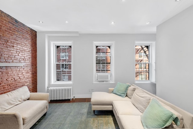 living area with radiator, brick wall, dark wood-style floors, recessed lighting, and baseboards