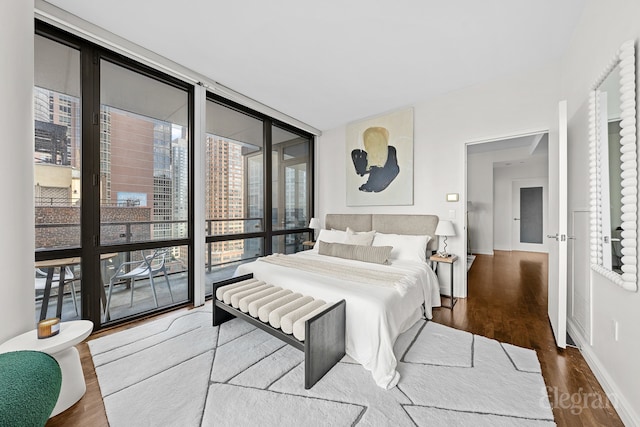 bedroom featuring a wall of windows, baseboards, and wood finished floors