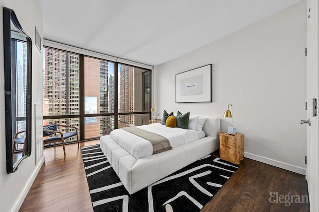 bedroom featuring a wall of windows, baseboards, and wood finished floors