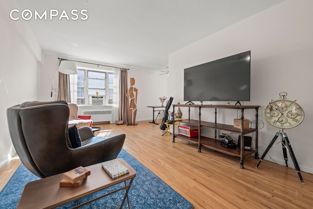 living area featuring radiator, wood finished floors, baseboards, and cooling unit