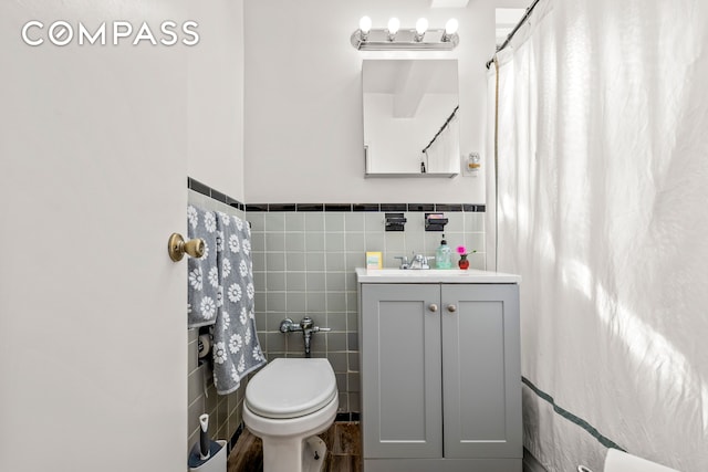 bathroom with vanity, tile walls, toilet, and wainscoting