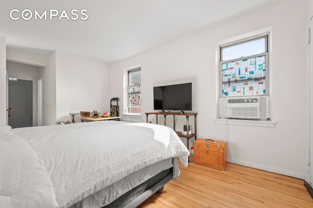 bedroom featuring multiple windows, cooling unit, light wood-type flooring, and baseboards