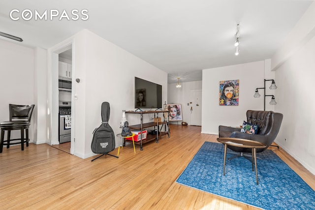 living area featuring track lighting, baseboards, and wood finished floors