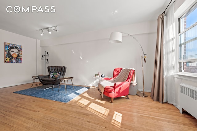 sitting room with wood finished floors, radiator, and a healthy amount of sunlight