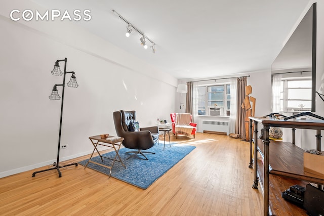 living area with track lighting, radiator heating unit, baseboards, and wood finished floors