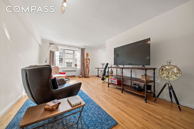 living room featuring radiator heating unit, baseboards, and wood finished floors