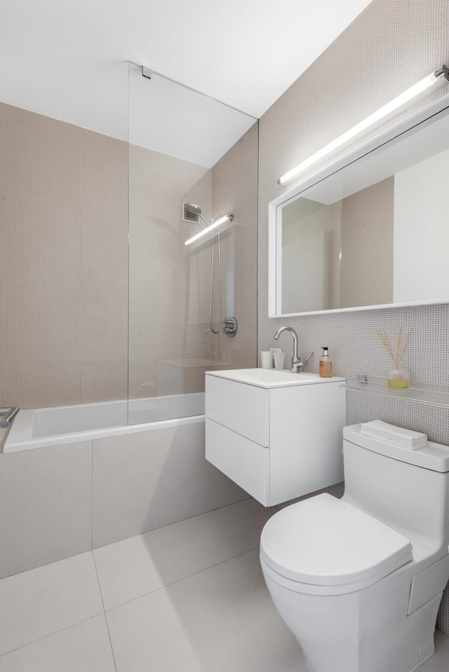 full bath featuring tile patterned floors, toilet, shower / washtub combination, tile walls, and vanity