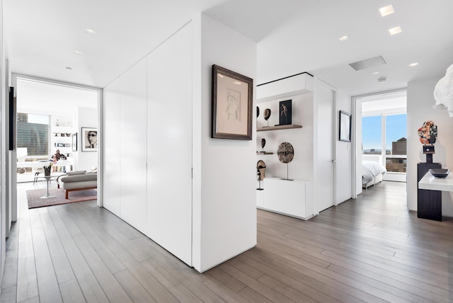 hall featuring a wall of windows, wood finished floors, and visible vents