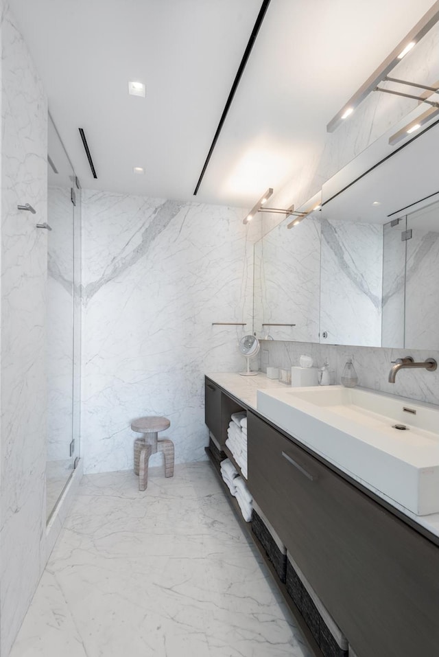 bathroom featuring vanity, stone wall, and a marble finish shower