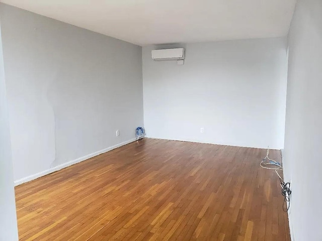 unfurnished room with wood-type flooring and a wall mounted AC