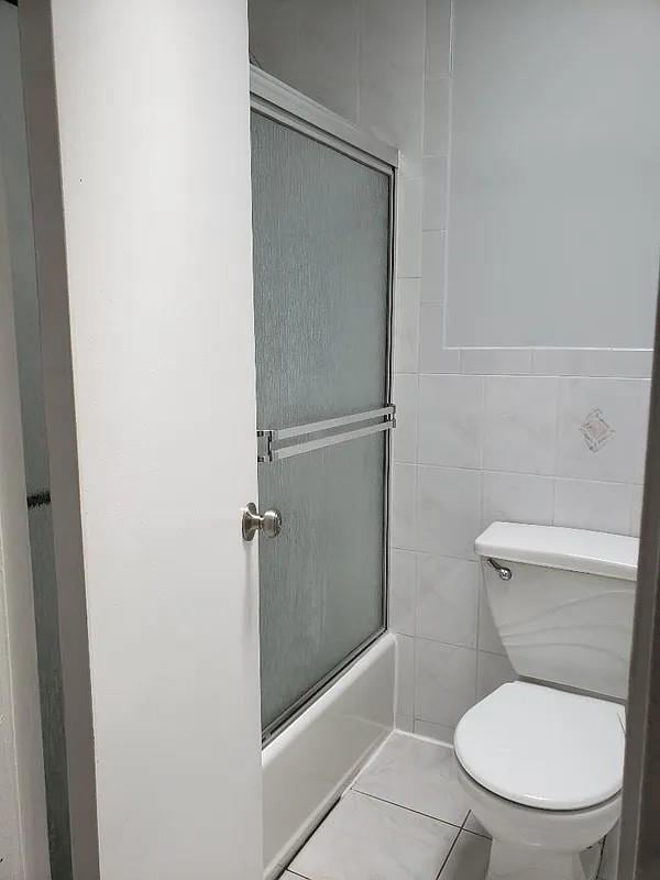 1207 E 83rd St, New York City, NY 11236 - bathroom featuring toilet, shower / bath combination with glass door, and tile patterned flooring