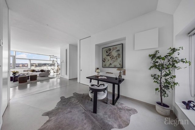 corridor featuring finished concrete floors and baseboards