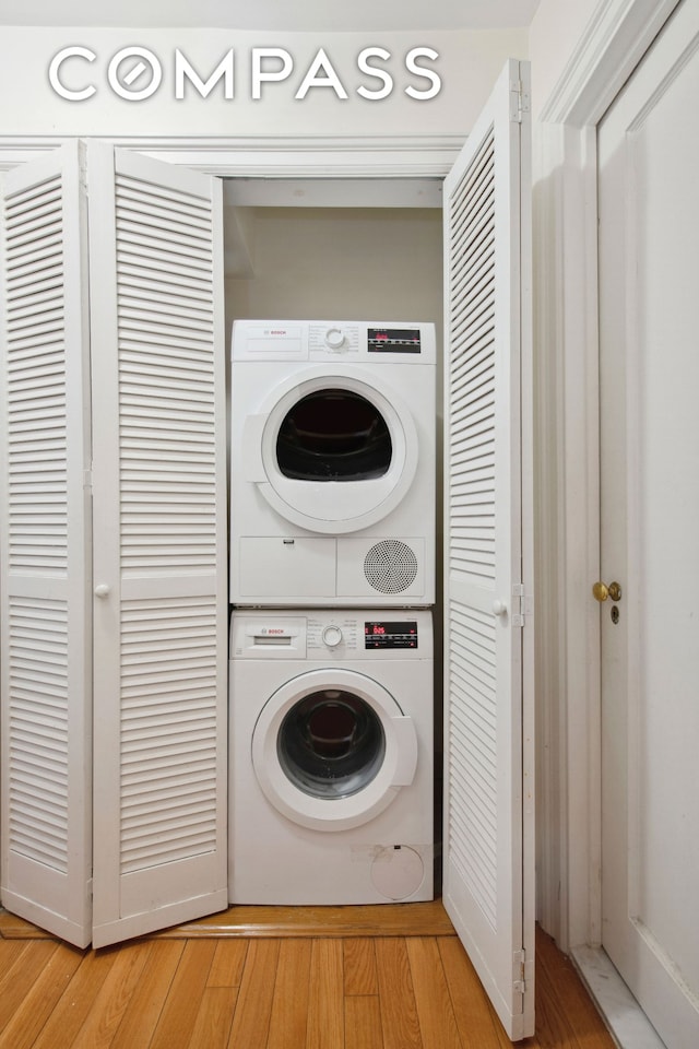 laundry area featuring laundry area, stacked washer and clothes dryer, and light wood finished floors