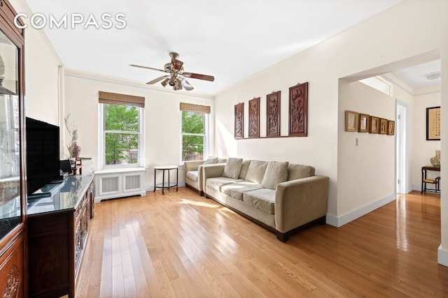 living area with a ceiling fan, radiator heating unit, light wood-style floors, and ornamental molding