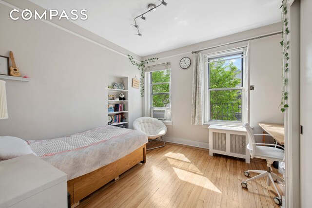 320 E 83rd St Unit 4De, New York City, NY 10028 - bedroom with radiator heating unit, track lighting, hardwood / wood-style flooring, baseboards, and cooling unit