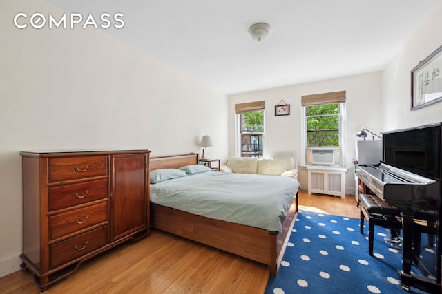 bedroom featuring cooling unit, radiator, and light wood-type flooring