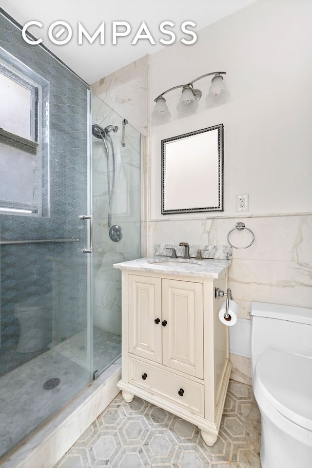 bathroom with vanity, toilet, tile walls, and a shower stall