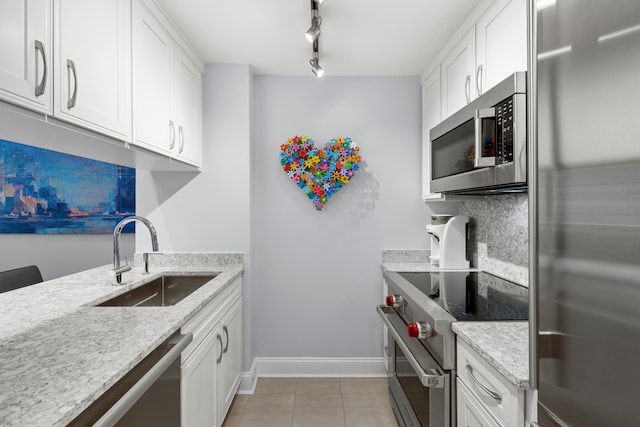 kitchen featuring a sink, appliances with stainless steel finishes, white cabinets, light tile patterned floors, and decorative backsplash