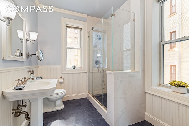 full bath featuring tile patterned flooring, wainscoting, a stall shower, and toilet