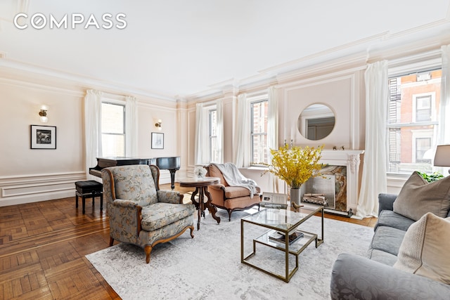 living room with a wealth of natural light, a decorative wall, a wainscoted wall, and ornamental molding