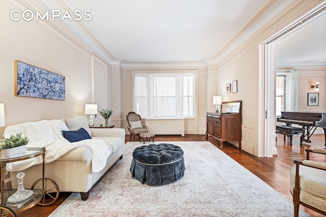 living room with a decorative wall, wood finished floors, a wainscoted wall, and ornamental molding