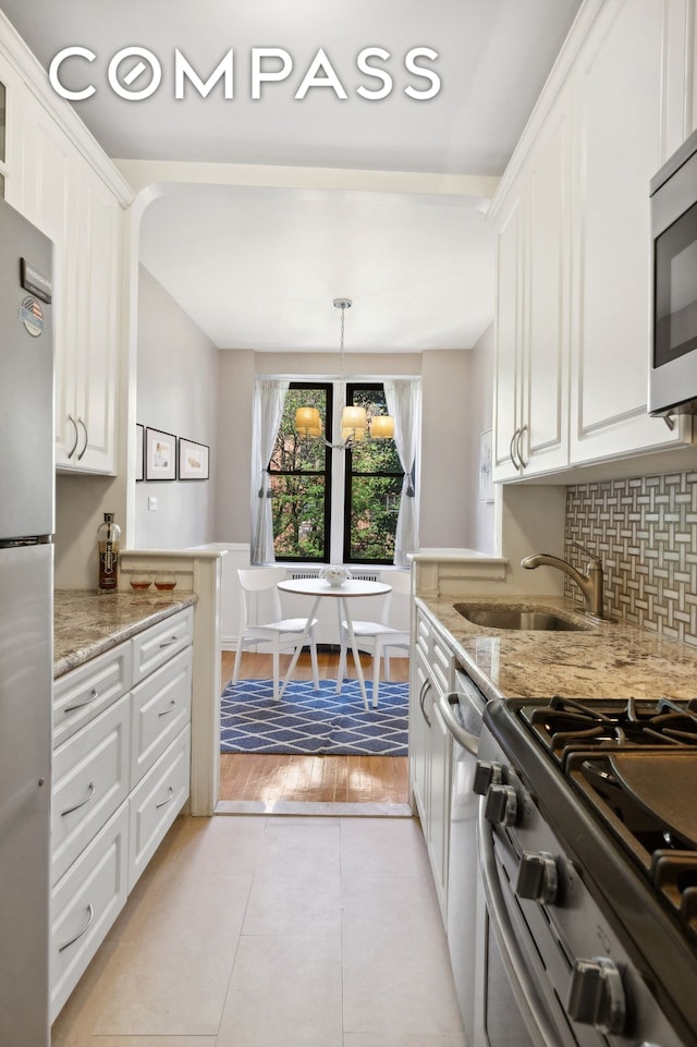 kitchen with light tile patterned floors, white cabinetry, stainless steel appliances, and a sink