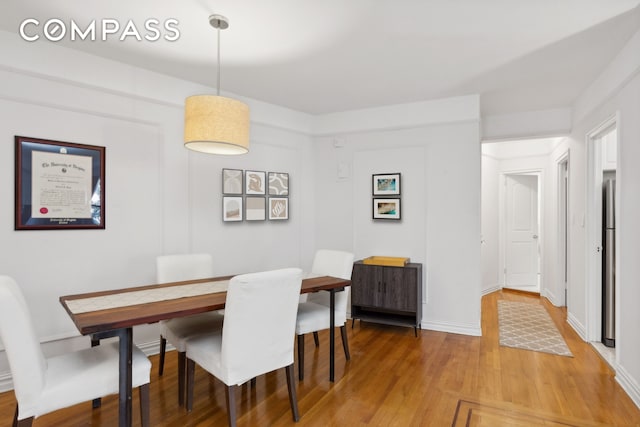 dining space with light wood-type flooring and baseboards