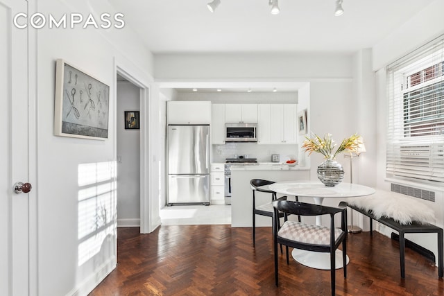 kitchen featuring tasteful backsplash, radiator heating unit, light countertops, stainless steel appliances, and white cabinetry