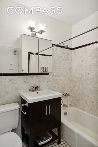 689 Fort Washington Ave Unit 4B, New York City, NY 10040 - bathroom featuring toilet, tile walls, shower / bath combo with shower curtain, tile patterned flooring, and vanity