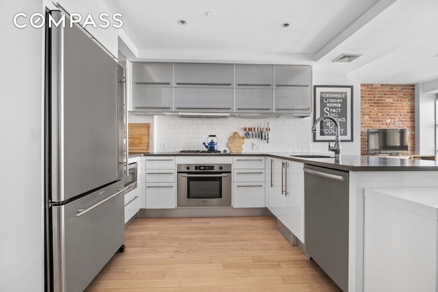 kitchen with visible vents, gray cabinets, a sink, stainless steel appliances, and dark countertops