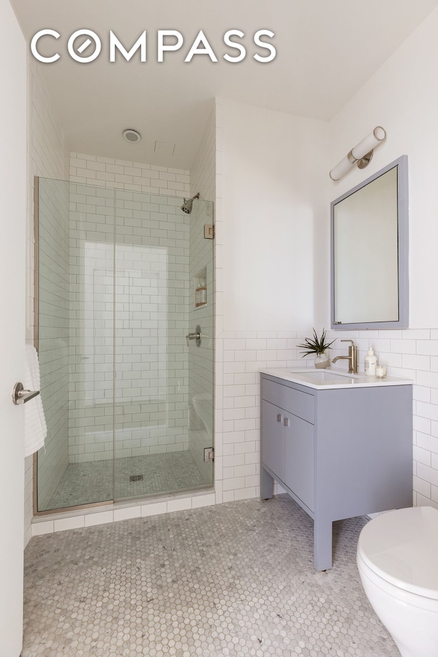 bathroom with tile patterned floors, tile walls, a stall shower, and vanity