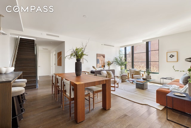 dining room with hardwood / wood-style flooring, stairway, visible vents, and expansive windows