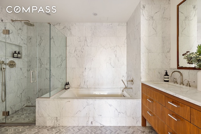 full bathroom featuring a marble finish shower, tile walls, and vanity