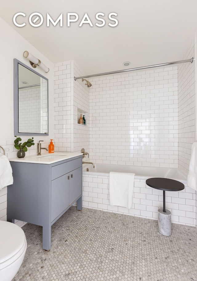 full bathroom with tile patterned floors, tiled shower / bath, toilet, and vanity