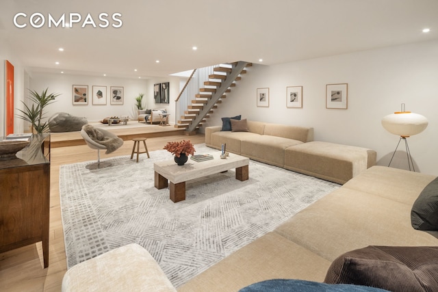 living room with recessed lighting, light wood-type flooring, and stairway