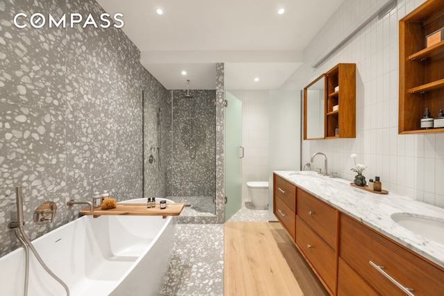 full bathroom with a sink, tile walls, a shower stall, double vanity, and a soaking tub