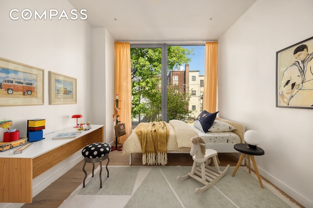 living area featuring wood finished floors, a wall of windows, and baseboards