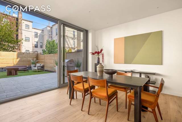 dining room featuring hardwood / wood-style floors, expansive windows, and baseboards