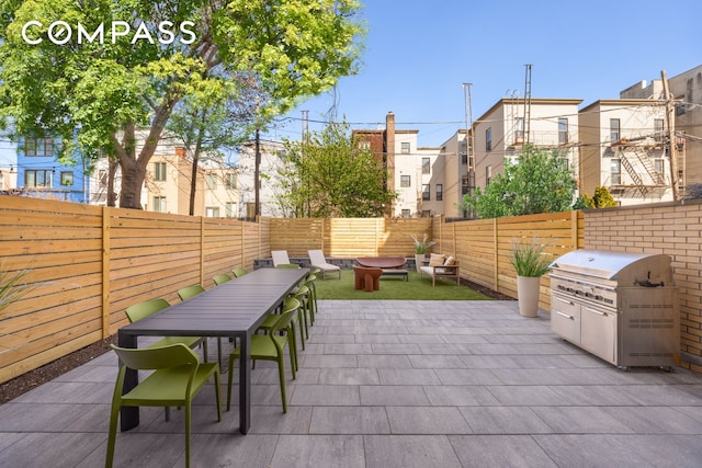 view of patio featuring outdoor dining space, a fenced backyard, grilling area, and a residential view