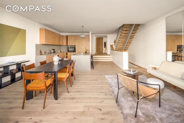 dining space featuring stairway, baseboards, and light wood-style floors