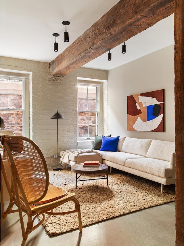 living area with beamed ceiling, brick wall, and a wealth of natural light