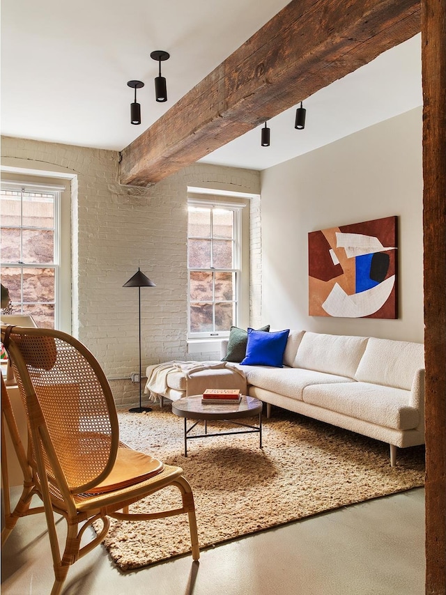 living room featuring plenty of natural light, beam ceiling, and brick wall