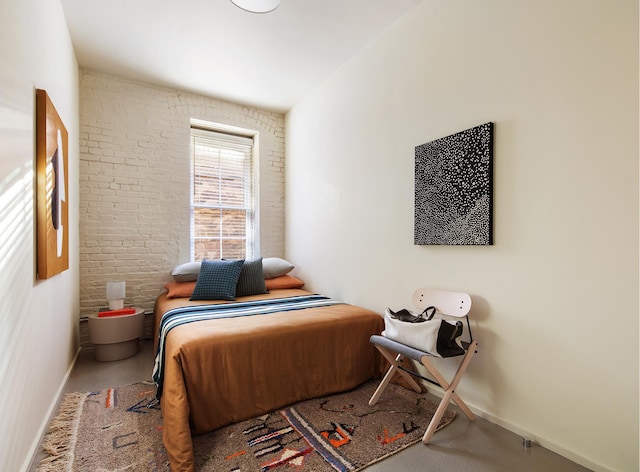 bedroom featuring baseboards and brick wall