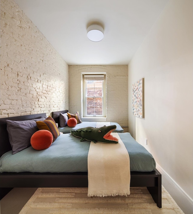 bedroom with brick wall and baseboards